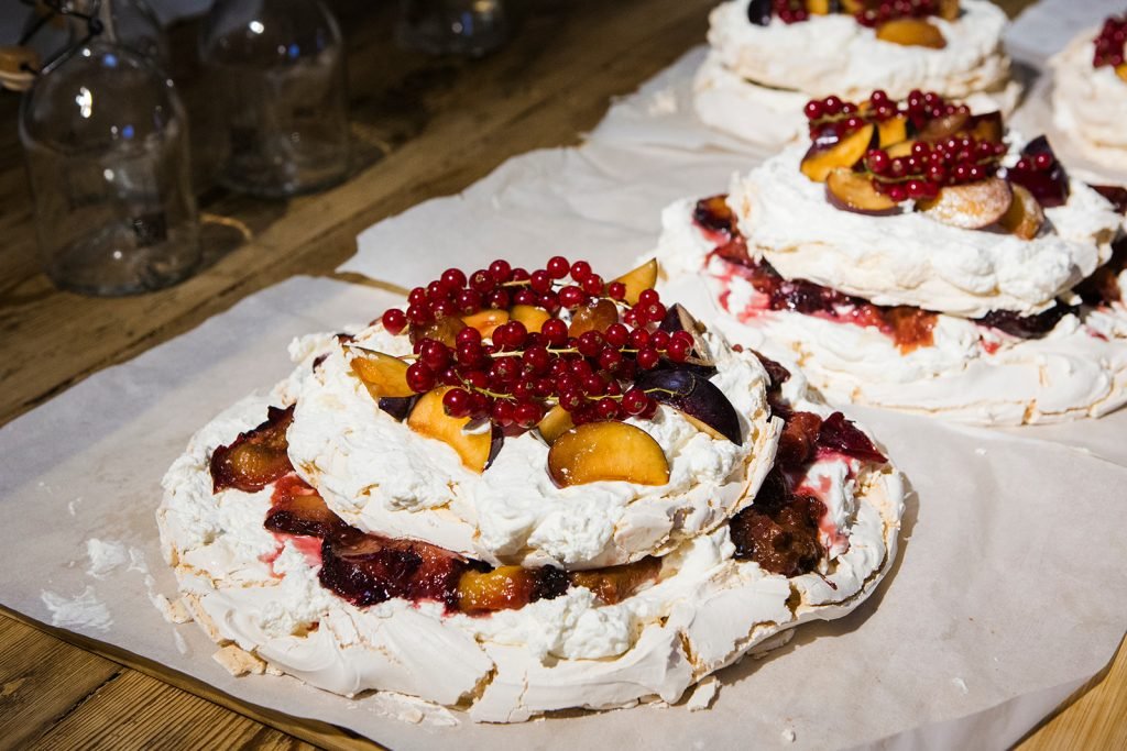 Outdoor destination wedding venue and catering details, featuring an outdoor fire setup and a berry pavlova cake. Destination wedding photographer Flor de Sal Photo.