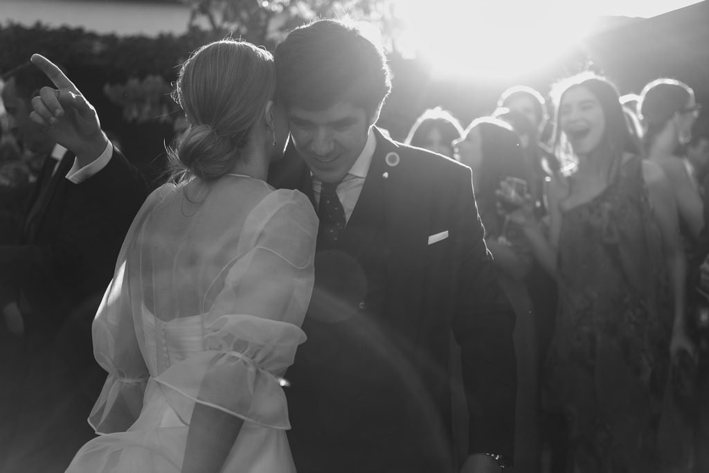 Black and white documentary photo of groom and friends celebrating spontaneously. Candid wedding photographer.